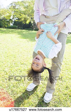 Stock Photo - Father holding daughter upside down. Fotosearch