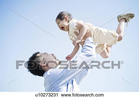 Stock Image - Father lifting up daughter. Fotosearch
