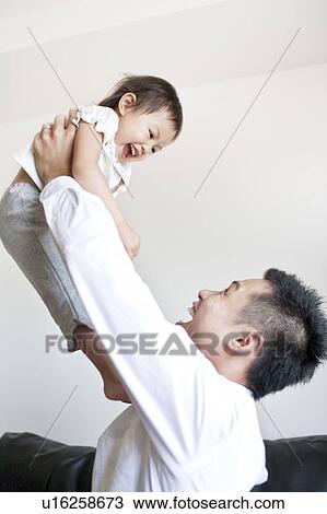 Stock Image - Father lifting up daughter. Fotosearch