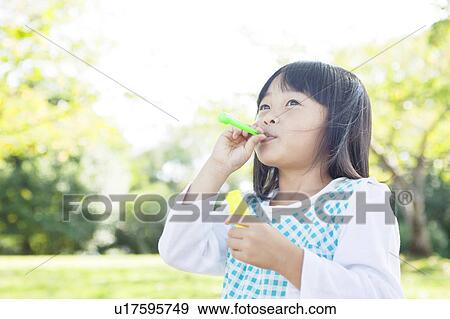 Girl blowing a bubble wand View Large Photo Image Stock Photo - Girl blowing a bubble wand. Fotosearch