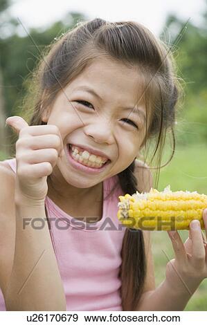 Stock Photo - Girl eating corn, Chiba Prefecture, Honshu, Japan. Fotosearch