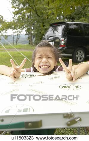 Stock Image - Girl Grinning and Showing Victory Sign. Fotosearch