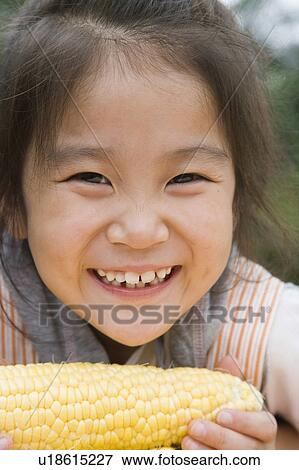 Stock Photo - Girl holding corn, Chiba Prefecture, Honshu, Japan. Fotosearch
