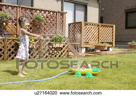 Stock Image - Girl playing with sprinkler, Chiba Prefecture, Honshu, Japan. Fotosearch