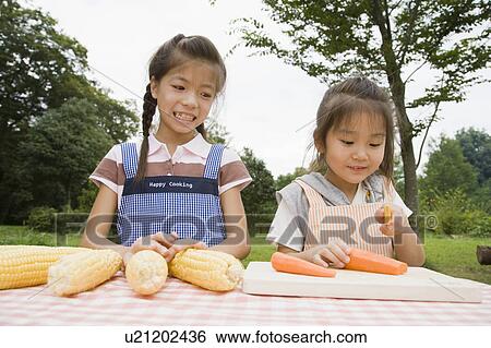 Stock Photograph - Girls chopping carrots, Chiba Prefecture, Honshu, Japan. Fotosearch