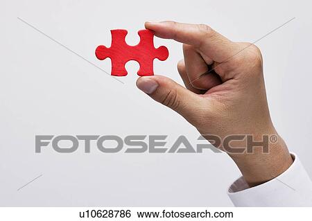 Stock Photograph - Hand holding Jigsaw Piece. Fotosearch