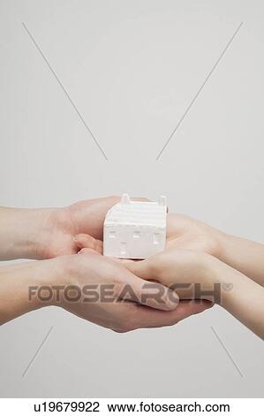 Stock Image - Holding a house with hands. Fotosearch
