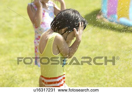 Stock Image - Kids playing with sprinkler, Chiba Prefecture, Honshu, Japan. Fotosearch
