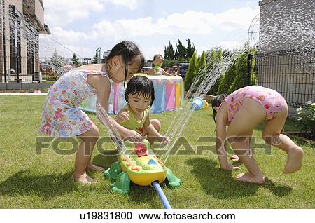 Stock Image - Kids playing with sprinkler, Chiba Prefecture, Honshu, Japan. Fotosearch
