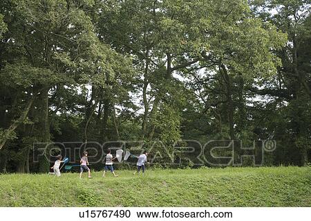Stock Image - Kids walking with butterfly nets to catch insects, Chiba Prefecture, Honshu, Japan. Fotosearch