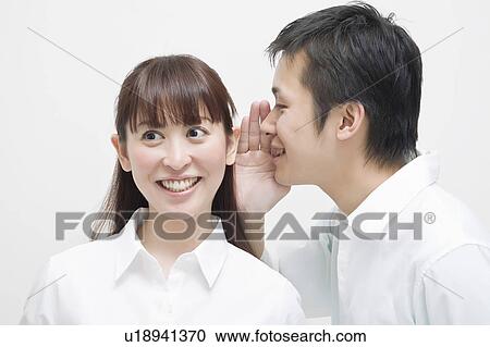Stock Image - Man whispering to woman. Fotosearch