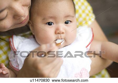 Mother feeding baby girl View Large Photo Image Stock Image - Mother feeding baby girl. Fotosearch