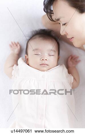 Stock Image - Mother next to sleeping baby. Fotosearch