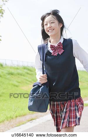 Stock Image - schoolgirl running, toothy smile. Fotosearch