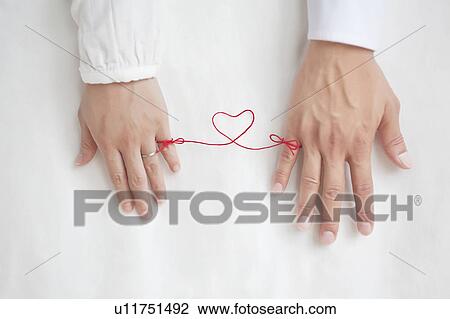 Stock Image - String on woman and man's pinkies tying them together. Fotosearch