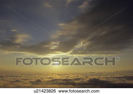 Stock Photograph - Sun Rising Above Clouds. Fotosearch