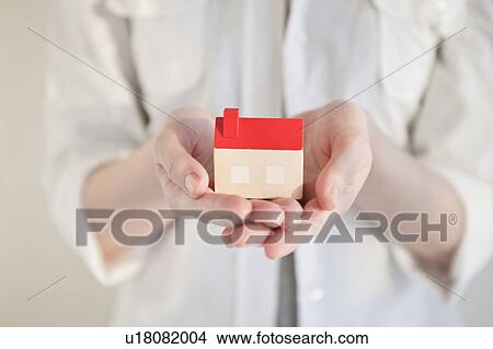 Woman holding a small house in her hand View Large Photo Image Picture - Woman holding a small house in her hand. Fotosearch