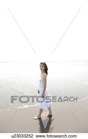 Stock Image - Woman looking at camera at beach, Ibaraki Prefecture, Honshu, Japan. Fotosearch