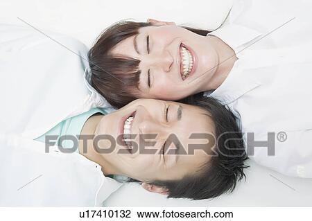 Stock Image - Young couple lying down smiling. Fotosearch