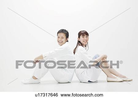 Young couple sitting back to back View Large Photo Image Stock Photograph - Young couple sitting back to back. Fotosearch