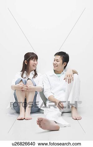 Stock Image - Young couple sitting side by side. Fotosearch