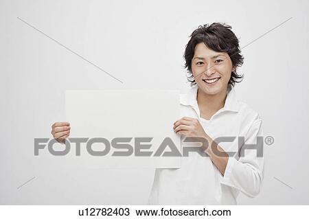 Stock Image - Young man holding a blank cardboard. Fotosearch