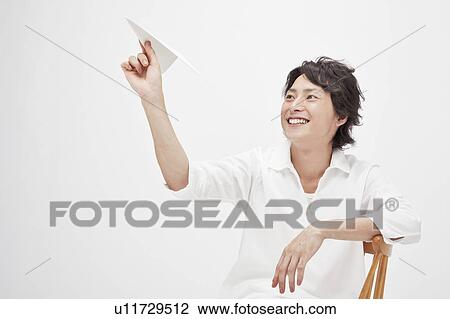 Stock Image - Young man holding a paper airplane. Fotosearch