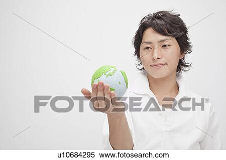 Young man looking at globe in his hand View Large Photo Image Stock Photography - Young man looking at globe in his hand. Fotosearch