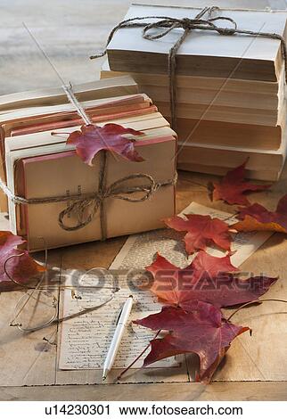 Stock Image - Autumn leaves on letter by books. Fotosearch