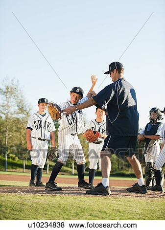 Stock Photo - Baseball coach and boys (10-11) standing on baseball diamond. Fotosearch