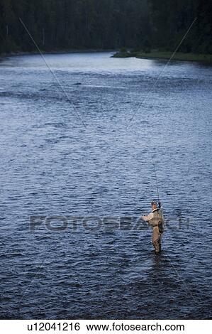 Stock Photograph - Canada, British Columbia, Fernie, Man fly fishing in river. Fotosearch