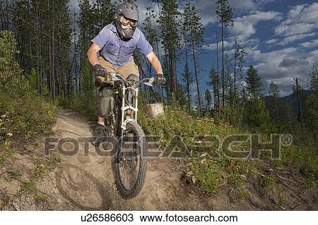 Stock Image - Canada, British Columbia, Fernie, Mid adult man enjoying mountain biking. Fotosearch