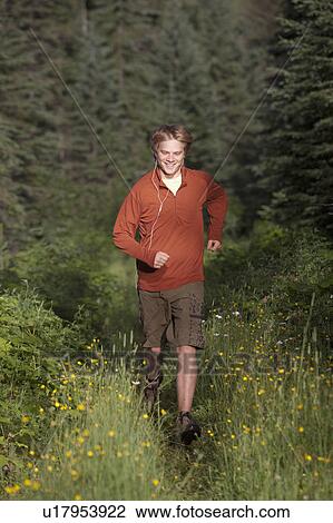 Stock Image - Canada, British Columbia, Fernie, young man jogging in forest. Fotosearch