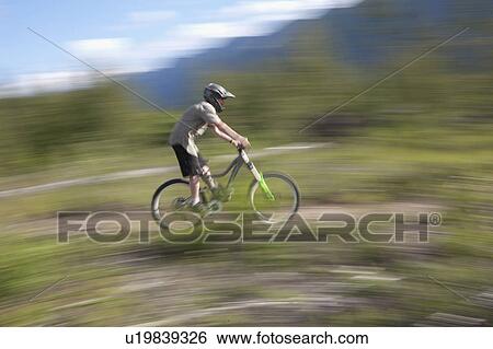 Stock Photograph - Canada, British Columbia, Fernie, Young man riding on mountain bike. Fotosearch