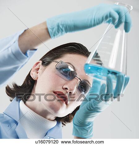 Stock Image - Female scientist examining chemical flask. Fotosearch