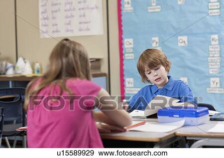 Girl (10-11) and boy (6-7) reading in classroom View Large Photo Image Stock Photo - Girl (10-11) and boy (6-7) reading in classroom. Fotosearch
