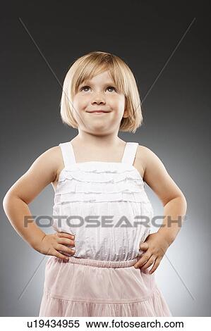 Stock Photography - Girl (2-3) with hands on hip and looking up, studio shot. Fotosearch