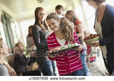 Stock Photo - Girls (10-11, 14-15) with family during celebration event. Fotosearch