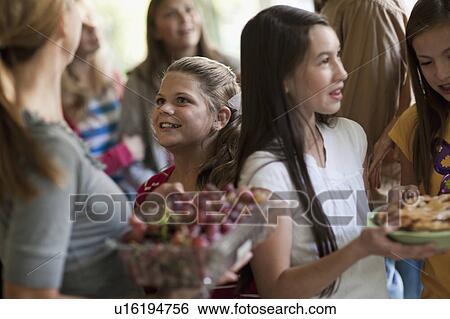 Stock Photograph - Girls (10-11, 14-15) with family during celebration event. Fotosearch