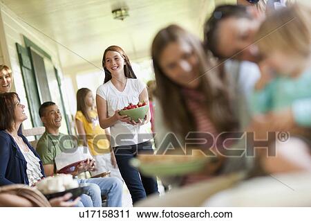 Stock Image - Girls (10-11, 2-3, 14-15) with father and family during celebration event. Fotosearch