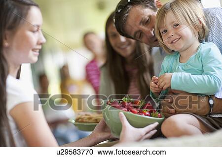 Stock Image - Girls (10-11, 2-3, 14-15) with father and family during celebration event. Fotosearch