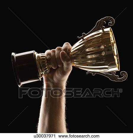 Hand holding trophy on black background View Large Photo Image Stock Image - Hand holding trophy on black background. Fotosearch