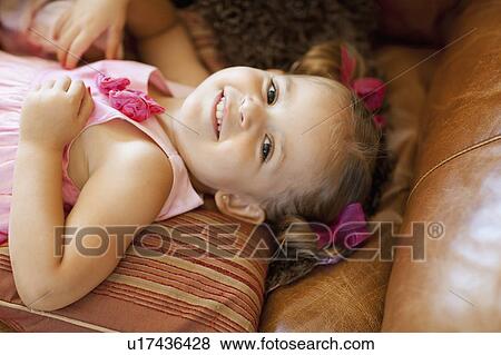 Stock Photo - Happy girl lying on sofa, high angle view. Fotosearch