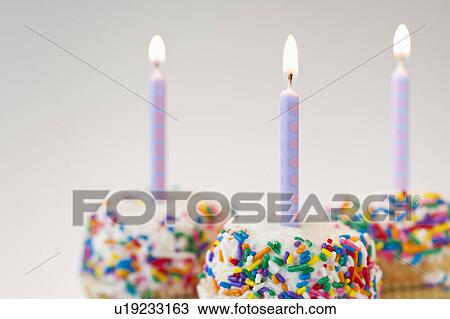 Stock Image - Lit candles on decorated cakes. Fotosearch