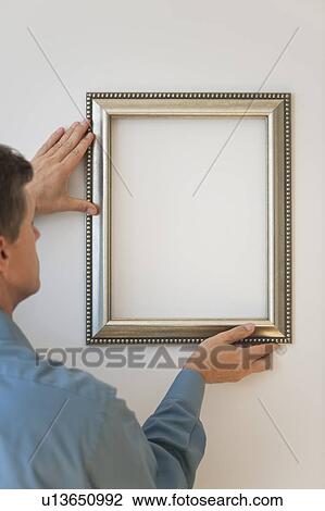Man hanging silver frame on wall View Large Photo Image Stock Image - Man hanging silver frame on wall. Fotosearch