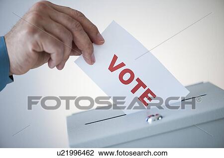 Stock Image - Man putting vote card into box. Fotosearch