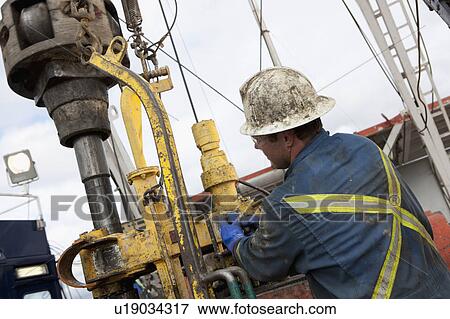 Stock Photo - Oil worker drilling for oil on rig. Fotosearch