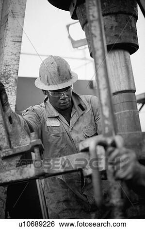 Stock Photograph - Oil worker drilling for oil on rig. Fotosearch