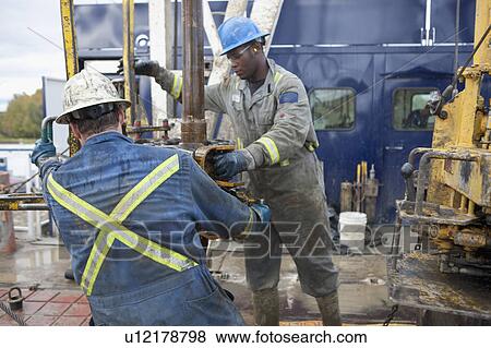 Stock Photo - Oil workers drilling for oil on rig. Fotosearch