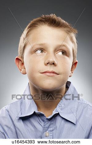 Stock Image - Portrait of boy (8-9) wearing shirt and looking away, studio shot. Fotosearch